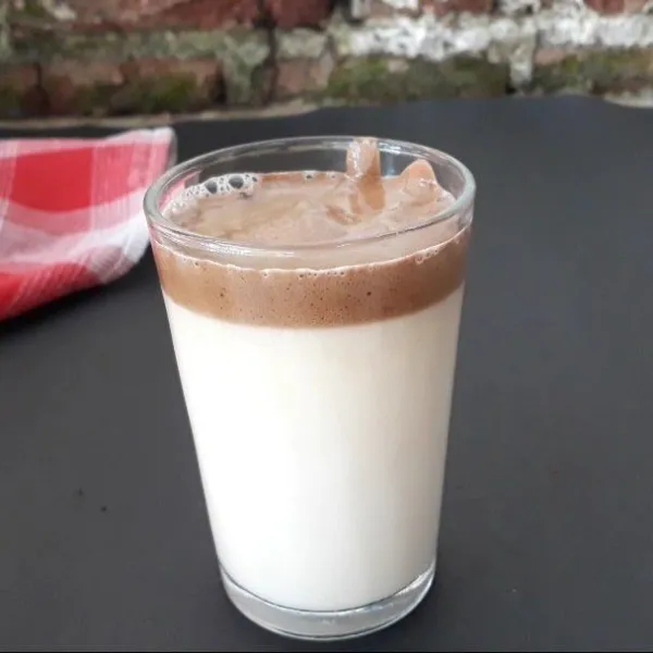 Tuang susu cair panas secukupnya dalam gelas, lalu tambahkan dalgona yang sudah dicampur dengan coklat bubuk tadi di atasnya. Kemudian beri taburan coklat bubuk.