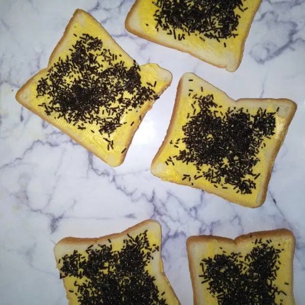 Olesi roti dengan margarin, taburi dengan meses.