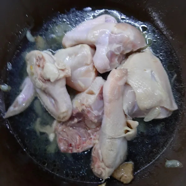 Masukkan ayam ke dalam tumisan jahe dan bawang putih, tambahkan 300ml air, masak sampai ayam berubah warna