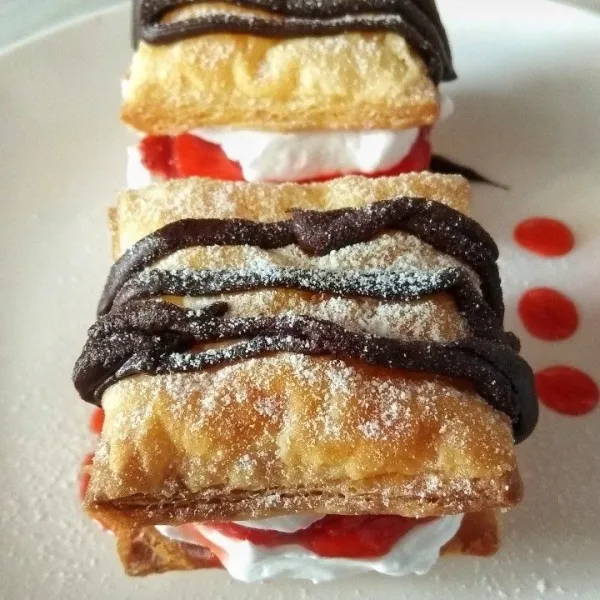 Tata puff pastry. Semprotkan whipped cream di layer paling bawah, lalu beri strawberry, semprot lagi dg whipped cream, lalu tutup dg puff pastry. Tuang coklat leleh diatas puff. Terakhir tabur gula halus. Kulkas sebelum disajikan.