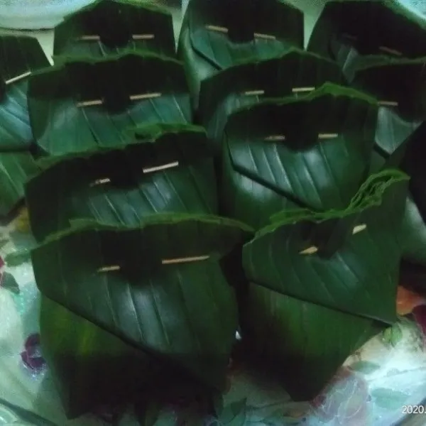 Ambil lembaran daun pisang yang sudah dipotong untuk ukuran bungkus, isi dengan adonan botok, bungkus bentuk tum, semat dengan lidi atau tusuk gigi.