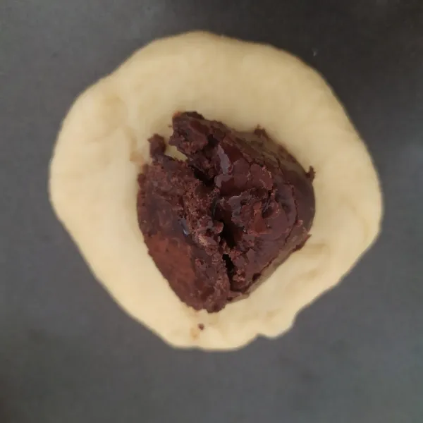 Pipihkan adonan isi dengan coklat, rapatkan dengan cara mencubit-cubit adonan sampai isian tertutup, simpan di baking paper yang sudah digunting-gunting. Lakukan sampai habis.