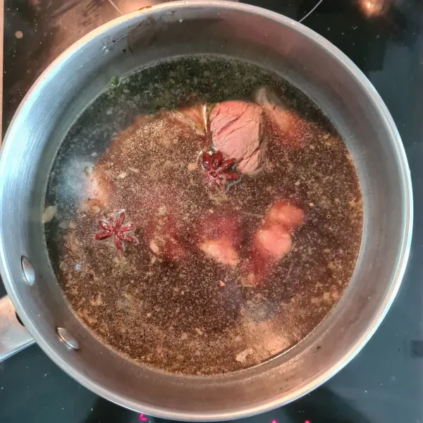 Masukkan air kaldu, kecap manis, kecap asin, kecap ikan, bunga lawang, dan kayu manis. Kecilkan api, tutup panci, lalu masak selama 1 jam.
