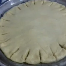 Letakkan adonan di loyang yang sudah dioles margarin dan ditabur tepung. Belah-belah pinggir adonan pizza kurang lebih 2 cm, beri irisan sosis atau keju, gulung dan pilin kesamping hingga selesai. Diamkan kembali 10 menitan.