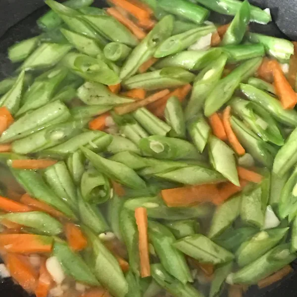 Tumis bawang putih, wortel, dan buncis, tambahkan air dan masak hingga matang