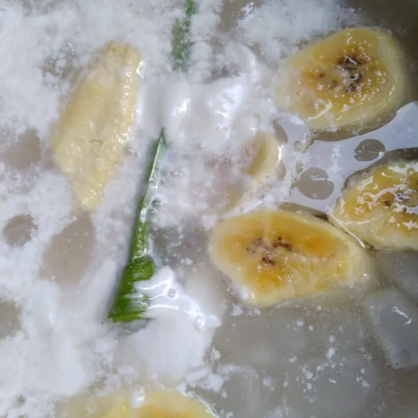 Setelah gula larut, masukkan pisang yang sudah dipotong dan daun pandan, tambahkan santan di aduk terus.