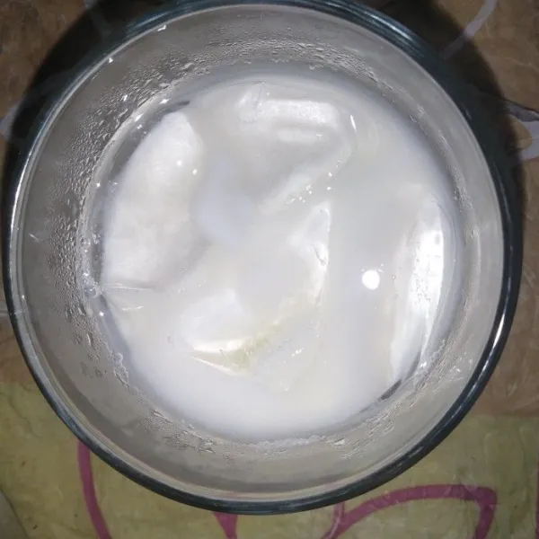 Tuang es batu dan susu ke dalam gelas.