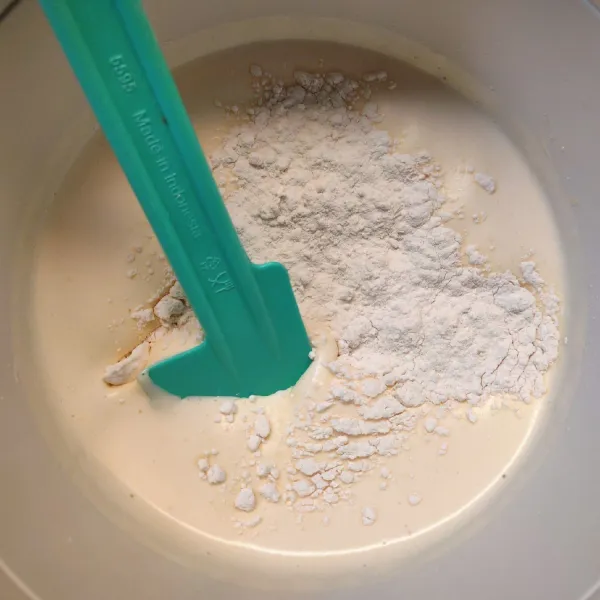 Matikan mikser, lalu masukkan sebagian tepung terigu, aduk dengan spatula secara perlahan.