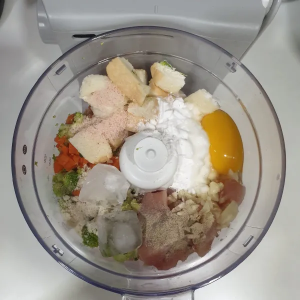 Masukkan ke dalam food processor, fillet ayam yang dipotong dadu, wortel, brokoli,  telur, bawang putih, tepung kanji kentang, es batu, merica, garam, dan chicken stock powder.