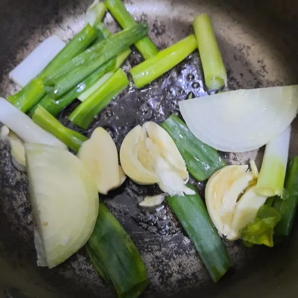 Tumis bawang bombay, daun bawang, dan tiga buah bawang putih yang sudah di geprek hingga wangi dan berubah warna.