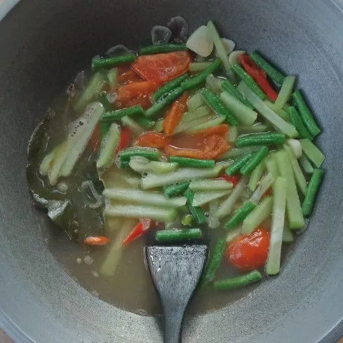 Masukkan air, masak sampai mendidih, lalu masukkan labu siam dan kacang panjang. Masak hingga ½ matang