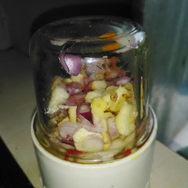 Haluskan bawang putih, bawang merah, jahe, kunyit, laos, dan serai menggunakan blender.