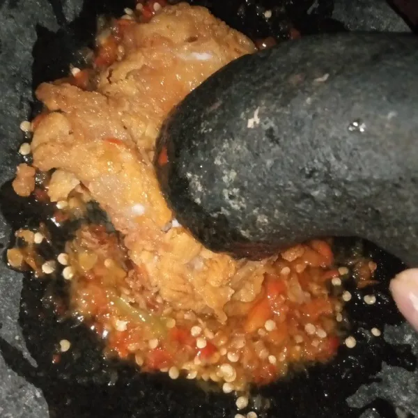 Ambil 1 potong ayam krispi, kemudian geprek di atas sambal. Tuangkan sisa sambal di atas permukaan ayam krispi