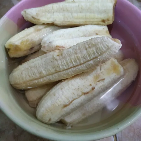Kupas pisang, rendam pisang di air supaya tidak menghitam.