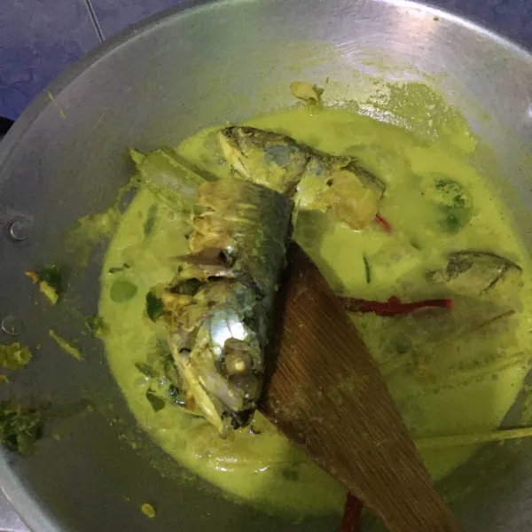 Masukkan santan, bumbu halus, daun salam, daun jeruk, serai dan ikan ke dalam wajan. Aduk terus hingga mendidih