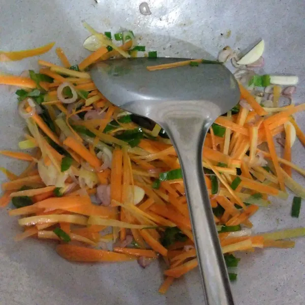 Tambahkan wortel yang dipotong tipis memanjang dan daun bawang, tumis hingga harum.