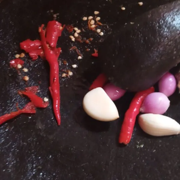 Siapkan cobek masukan bawang putih, bawang merah, cabai rawit merah, dan cabe merah, lalu uleg sampai halus. Tambahkan gula merah dan garam