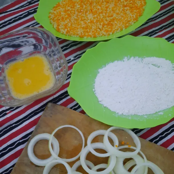 Celupkan bawang bombay ke tepung sajiku. celupkan kedalam kocokan telur. Lalu celupkan ke tepung roti secara merata.