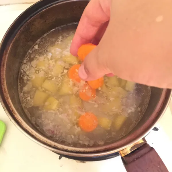 Masukkan wortel, kentang, sosis dan daun salam.