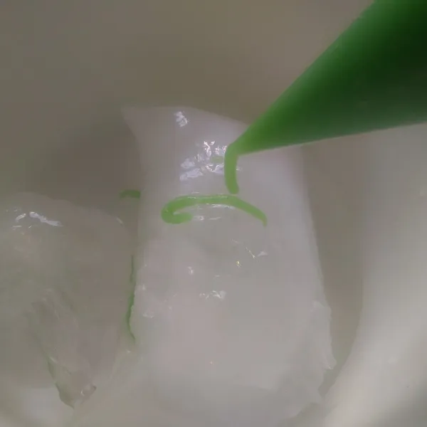 Siapkan air dan es batu. Masukkan adonan cendol ke dalam plastik segitiga gunting bagian ujungnya.