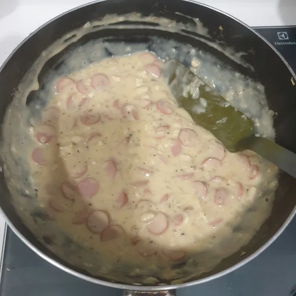 Masukkan sosis, saus carbonara, garam, dan lada hitam, masak sampai mendidih, dan terakhir masukkan keju cheddar yang diparut, aduk rata. Matikan api.