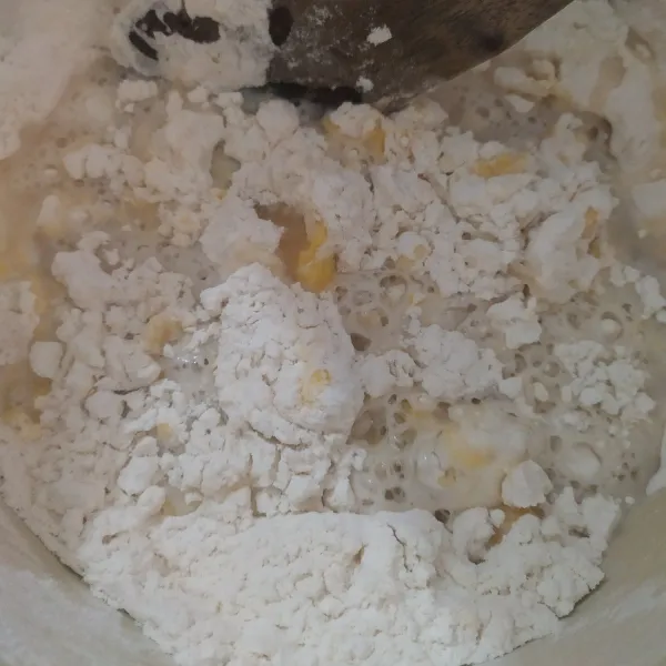 Tuang air larutan gula ke dalam adonan, aduk kembali dengan spatula.