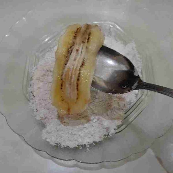 Ambil pisang, geprek lalu masukkan dalam adonan tepung terigu dan susu bubuk. Bolak balik pisang sampai merata. Angkat.