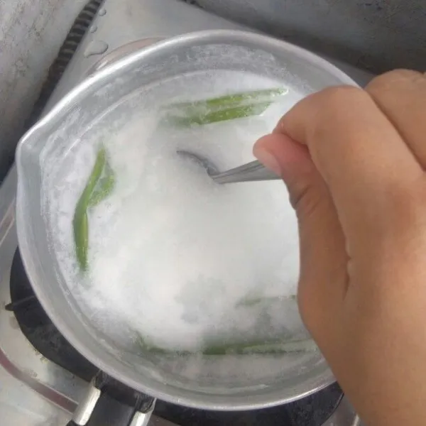 Rebus air bersama 2 lembar daun pandan yang di simpulkan, lalu tambahkan santan instan sambil terus di aduk agar santan tidak pecah.