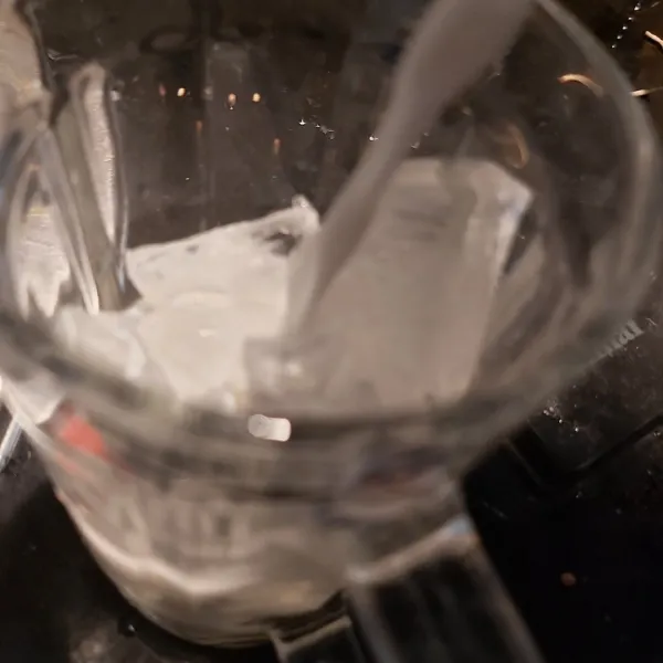 Siapkan es batu dalam gelas, lalu tambahkan susu segar.