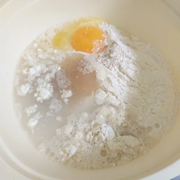Tambahkan juga telur dan air agak hangat. Aduk rata perlahan sampai tercampur rata.