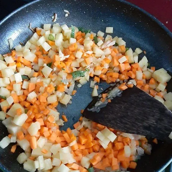 Masukkan ayam cincang, masak sebentar lalu masukkan kentang, wortel, dan daun seledri.