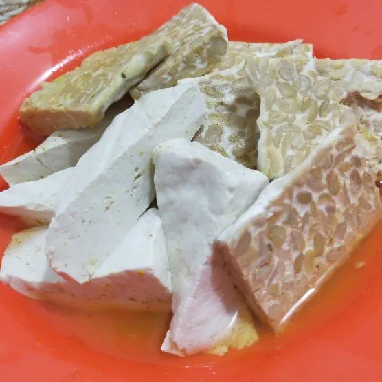 Rendam tempe dan tahu dalam air garam dan sedikit kunyit bubuk.