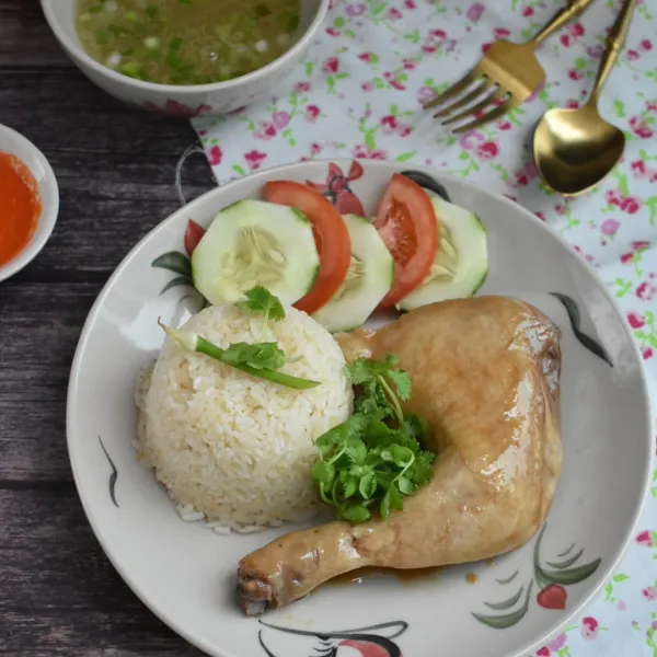 Sajikan hainan chicken rice dengan saus cabe dan kuah sup kaldu ayam.