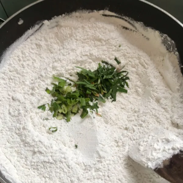 Sangrai tepung beras 10-15 menit lalu masukkan irisan daun kunyit dan daun bawang, setelah sangrai sisihkan.