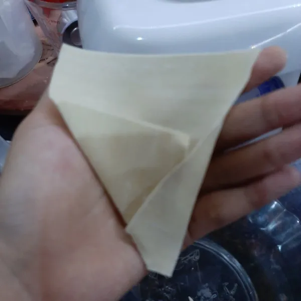 Lipat kulit pangsit menjadi segitiga seperti di atas.