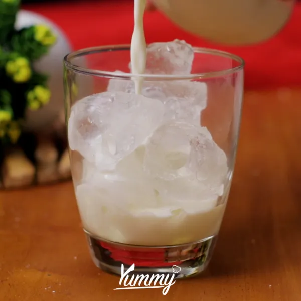 Tuangkan susu cair ke dalam gelas yang telah berisi es batu.