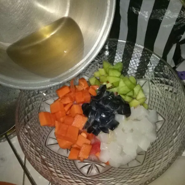 Setelah dingin, masukkan air gula ke dalam wadah buah, beserta susu kental manis.