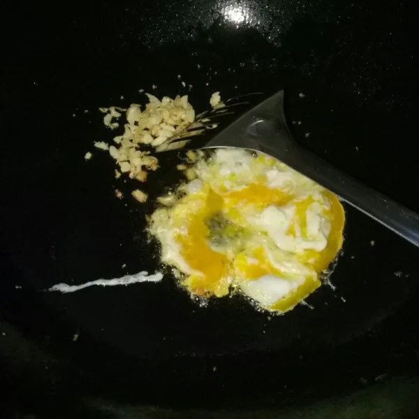 Siapkan pan, panaskan minyak. Tumis bawang putih sampai harum sisihkan di pinggir pan, lalu ceplokan telur aduk orak arik sampai matang