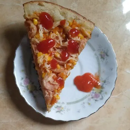 Setelah matang, potong-potong, sajikan pizza dengan saos tomat dan saos sambal sesuai selera.