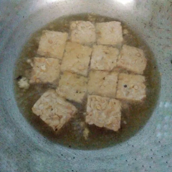 Tempe dicuci bersih. Kemudian potong-potong. Goreng setengah kering. Tiriskan dari minyaknya.