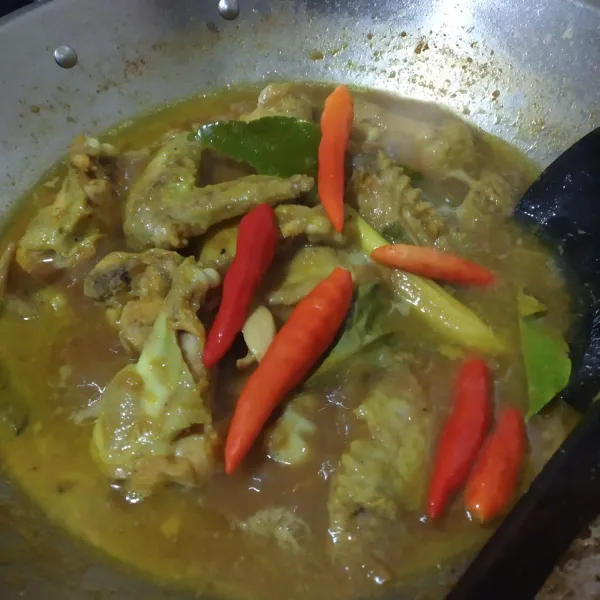 Jika ayam sudah empuk dan matang, tambahkan cabe utuh. Aduk-aduk lalu biarkan sampai cabe layu.