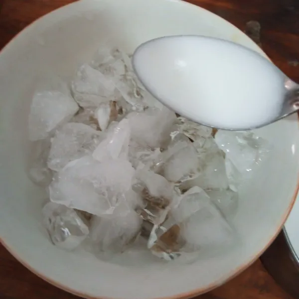 Sajikan kacang hijau di mangkok saji, tambahkan es batu dan kuah santan.