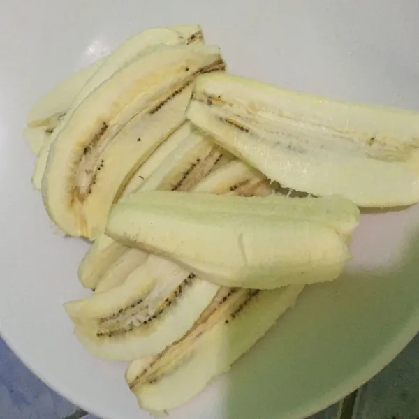 Kupas dan potong pisang jadi dua bagian. Sisihkan.