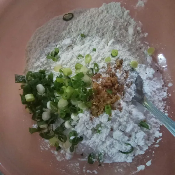 Campur tepung tapioka, tepung terigu, bumbu halus, kaldu bubuk dan daun bawang dalam satu wadah kemudian aduk rata lalu buat lubang di tengahnya.