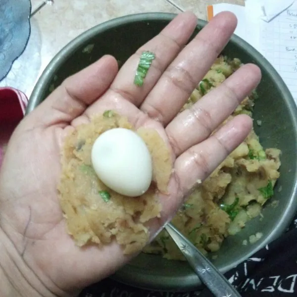 Ambil sesendok adonan, pipihkan isi dengan sebutir telur puyuh lalu bentuk bulat.