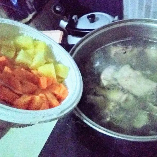 Setelah ayam agak empuk, masukkan wortel dan kentang, masak hingga empuk.