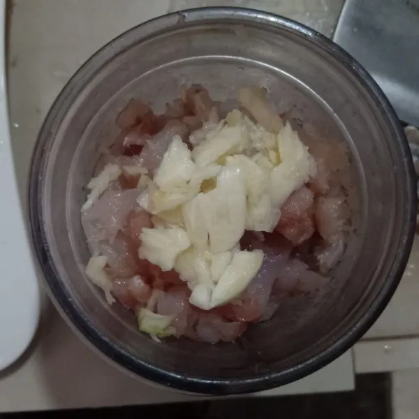 Geprek bawang putih, haluskan bersama daging ikan dan 1/4 bagian air ke dalam blender. Blender hingga halus