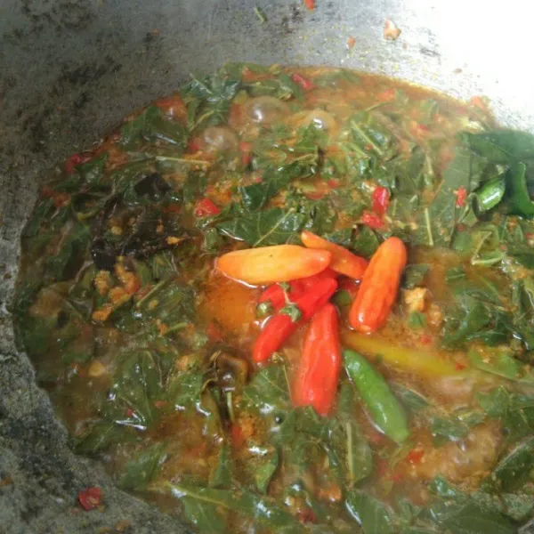 Masukkan daun singkong, tambahkan air, garam dan gula merah, masak hingga kuah agak menyusut, tambahkan cabe rawit utuh.