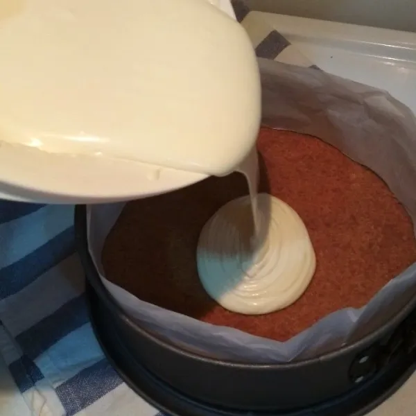 Masukkan adonan cheesecake ke dalam cetakan yg tadi berada di freezer, masukkan adonana secara perlahan agar udara yg ada tidak masuk terlalu banyak dan bisa menghasilkan cheesecake yg padat. lalu masukkan cheesecake kedalam oven, dan oven selama 45-50 menit tergantung dari kemampuan oven. setelah 45 menit lihat kembali cheesecake jika bagian tengah dari adonan sedikit "jiggly" atau "bergetar" saat di goyang berarti cheesecake sudah matang, buka penutup oven dan ganjal dengan spatula kayu atau semacamnya agak tidak tertutup rata. diamkan selama kurang lebih 6 jam sampai adonan bersuhu ruangan.