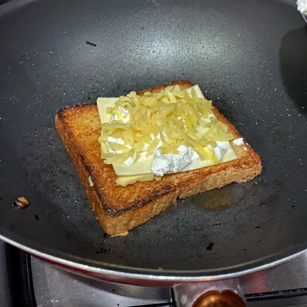 Balik roti, lalu taruh semua keju diatas sisi roti yang sudah garing.